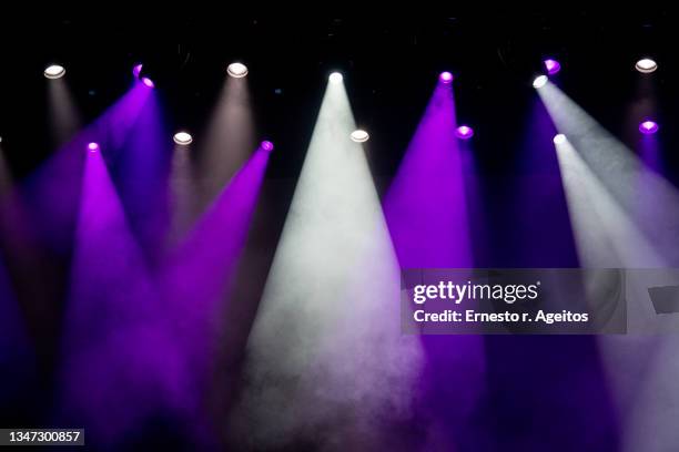 multiple light beams over a stage with fog - spotlicht elektrisch licht stockfoto's en -beelden