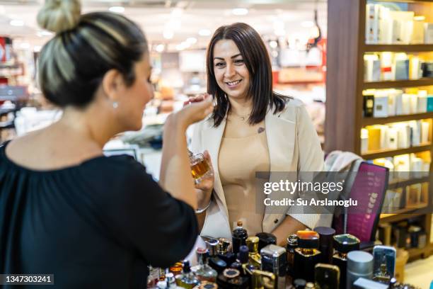 mujer adulta dueña de una perfumería ofrece nuevas fragancias a su cliente - perfumería fotografías e imágenes de stock