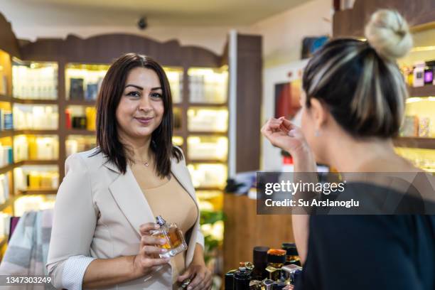 adult woman who owns a perfume shop offers new fragrances to her customer - sales kick off stock pictures, royalty-free photos & images