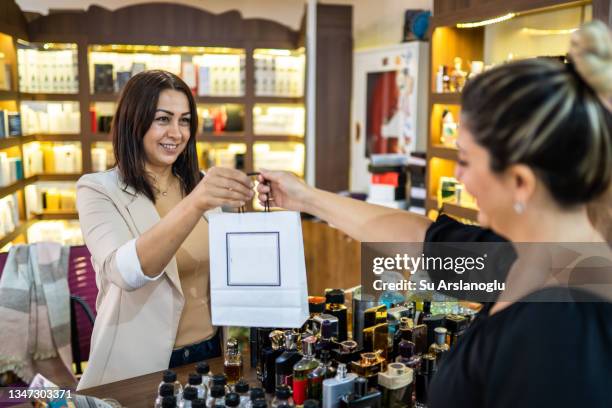 la mujer dueña de una perfumería entrega los perfumes recién comprados de su cliente - perfumería fotografías e imágenes de stock