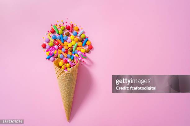 ice cream cone and colorful candies on pink - ice cream sprinkles stock pictures, royalty-free photos & images