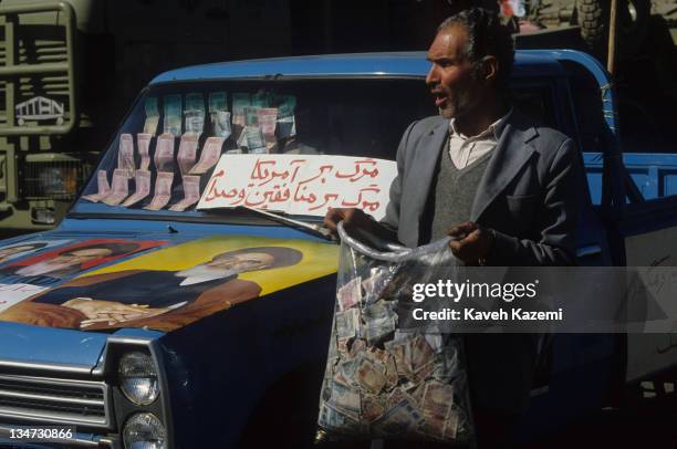 Man collects cash donations for troops on the Iran-Iraq front outside Tehran University, during a ceremony for the 7th anniversary of the Iranian...