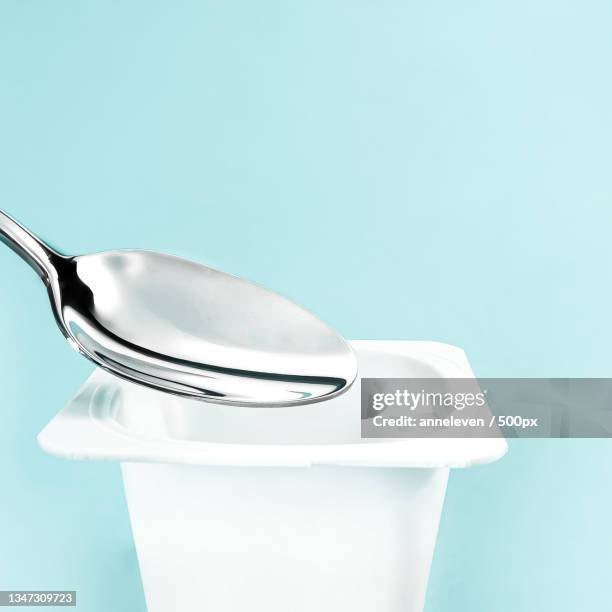 close-up of spoon against blue background - yoghurt pot stock-fotos und bilder