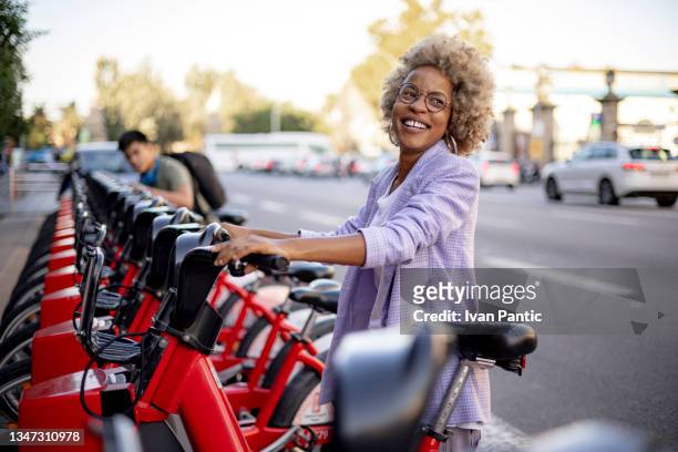 happy diverse couple of friends renting electric bicycles together - electric bike stockfoto's en -beelden