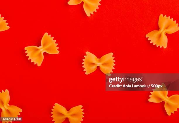 directly above shot of pasta on red background - bow tie pasta stock pictures, royalty-free photos & images