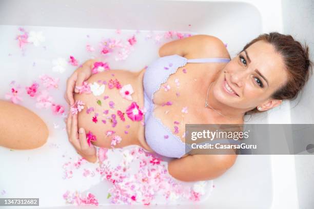 hermosa joven embarazada en el tercer semestre relajándose en un baño de leche - taking a bath fotografías e imágenes de stock