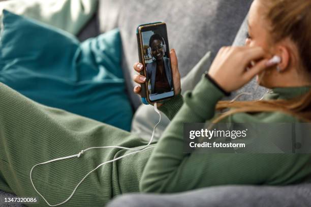 copy space shot of teenage girl lounging on the sofa and chatting with a friend over a video call - lying on back girl on the sofa stock pictures, royalty-free photos & images