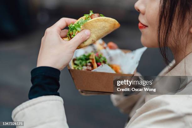 young woman taking lunch break and enjoying tacos in street food market - mexican street market stock pictures, royalty-free photos & images
