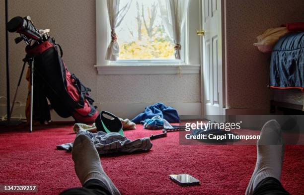feet wearing socks with smart phone, dirty laundry, and golf clubs by window - change socks stockfoto's en -beelden
