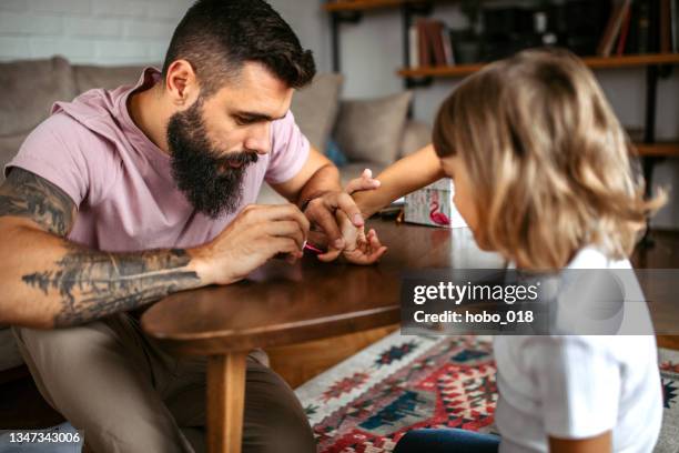 padre joven aplicando esmalte de uñas en las uñas de los dedos de la hija - body art painting fotografías e imágenes de stock