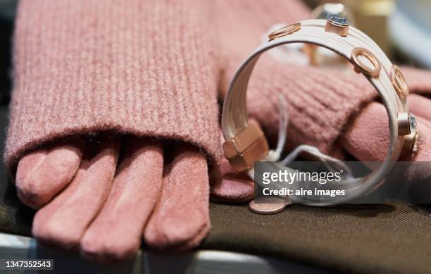 close view of a rose color sweaters' sleeve, gloves and a bracelet in a store's vitrine.a rose color sweater, gloves and a white bracelet is shown in a store's vitrine. - bracelet tissu photos et images de collection