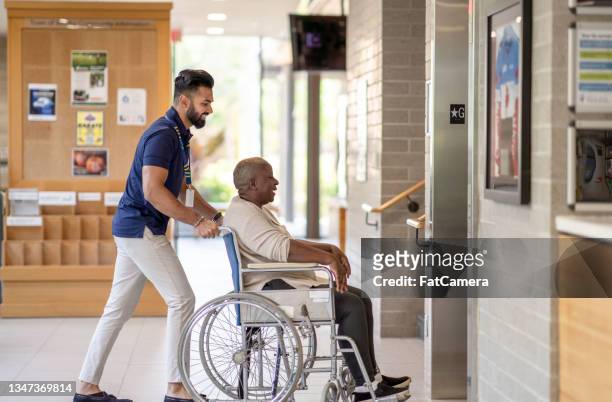un homme pousse une femme âgée dans son fauteuil roulant dans l’ascenseur - accessibilité aux personnes handicapées photos et images de collection