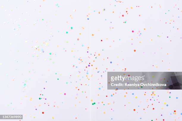 white background with scattered colorful confetti. holiday pattern wallpaper. flat lay, top view. party arrangement with copy space for text - coriandoli foto e immagini stock