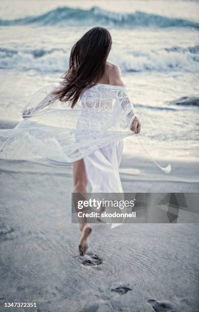 beautiful brunette girl with long hair in white dress at sunset stock photo - woman long dress beach stock pictures, royalty-free photos & images