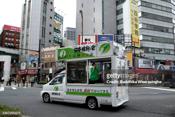 Japan Innovation Party member and Governor of Osaka Prefecture Hirofumi Yoshimura waves to voters from an election campaign car during the official...