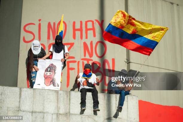 Group of demonstrators wave a Colombian flag with red paint resembling blood and the message 'If there is no peace there will be no football' at El...