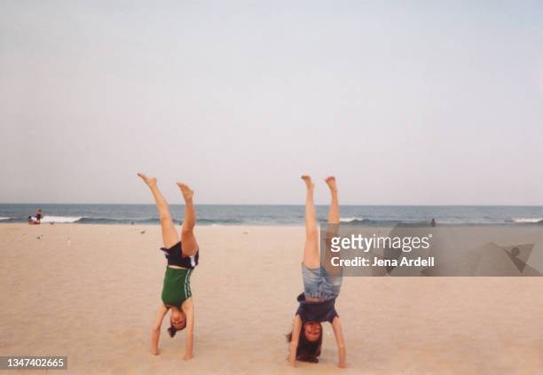 best friends doing handstands on beach, vintage 1990s teens on spring break - 90s teens stock-fotos und bilder
