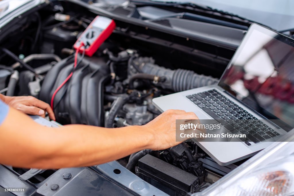Mechanic man using laptop examining tuning fixing repairing car