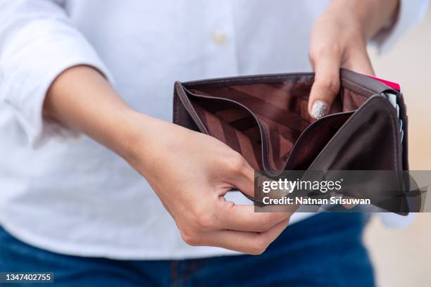 woman opening an empty wallet - geld verheizen stock-fotos und bilder