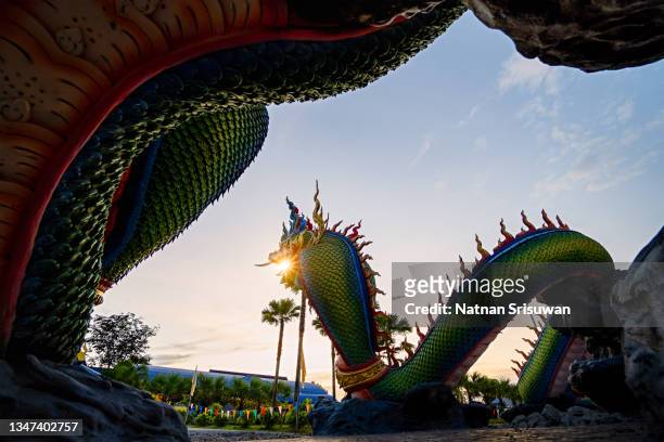 the sun sparkles through the mouth of a mythical serpent (naga) statue - sunbeam snake stock pictures, royalty-free photos & images