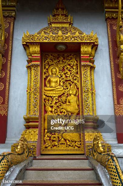 Entry portal with gilded carvings depicting mythical creatures and scenes from the life of Buddha, Temple Wat Nong Sikhounmuang, Luang Prabang, Laos.