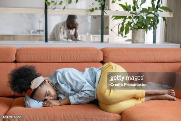 woman curled up on sofa - woman curled up stock pictures, royalty-free photos & images