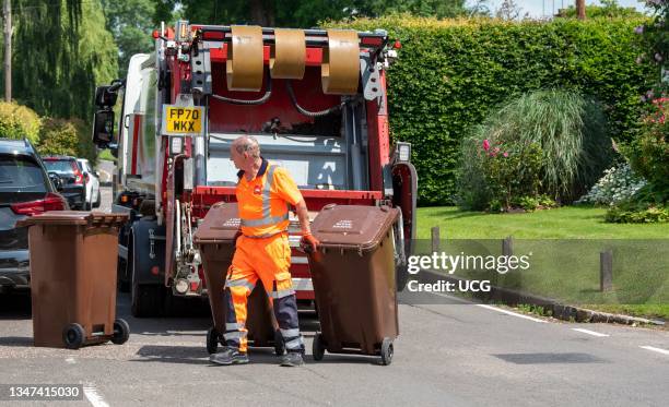 Hampshire, England, UK, Council operative returning garden waste bin to household after being tipped into a lorry for composting.