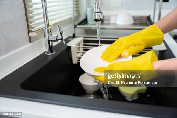 close up hands of housewife wear yellow rubber gloves washing dishes in the kitchen sink, maid - white glove cleaning stock pictures, royalty-free photos & images