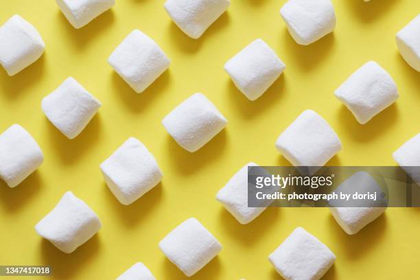 rows of white marshmallow on yellow background - marshmallow stock-fotos und bilder