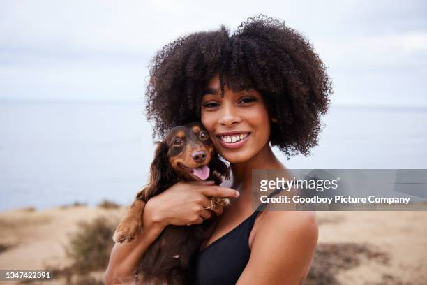 joven sonriente sosteniendo a su lindo perrito perro salchicha junto al océano - teckel fotografías e imágenes de stock