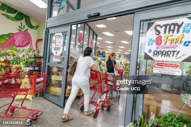 Florida, Miami Beach, Trader Joe's Supermarket, woman entering pushing shopping cart, Social distancing signs on door.