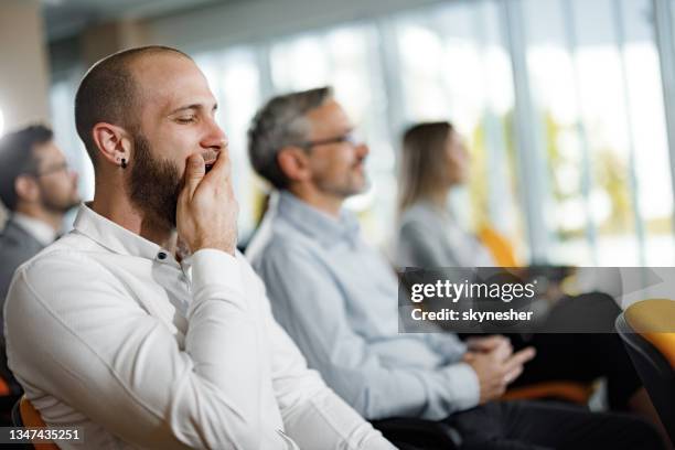 müder geschäftsmann gähnt bei bildungsveranstaltung im vorstandssaal. - yawn office stock-fotos und bilder