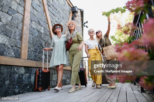 low angle view of senior women tourists with suitcases arriving to hotel. - summer spa stock pictures, royalty-free photos & images