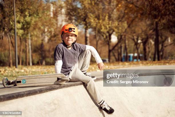portrait of boy with scooter in skate park - roller skate stock-fotos und bilder