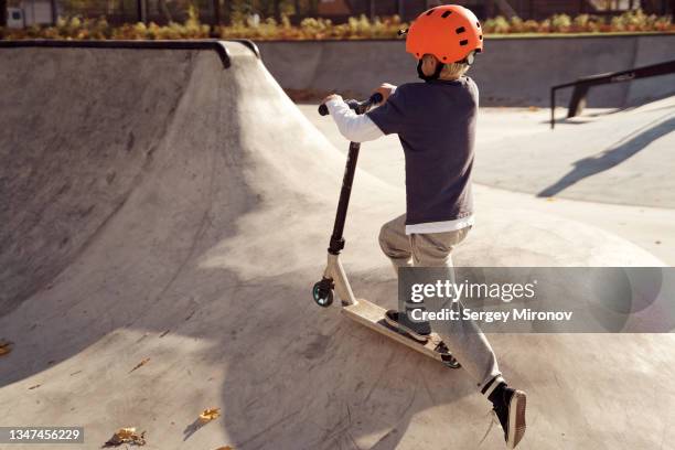 boy skating on scooter in skate park - roller skates stock-fotos und bilder