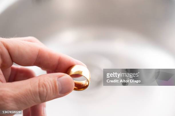 a person is holds a a wedding ring close to a a sink. - men rings foto e immagini stock