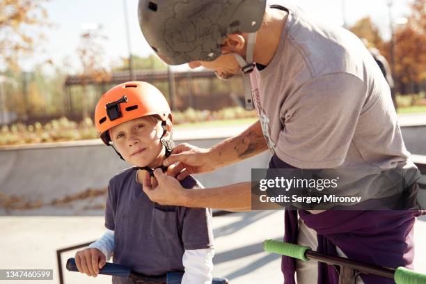 father with son skating on scooter in skate park - roller skate stock-fotos und bilder