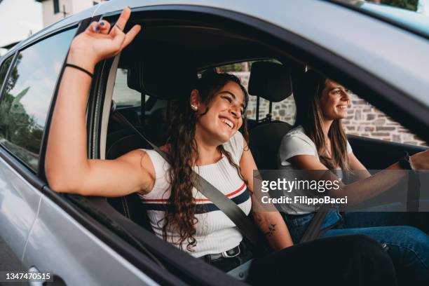 zwei junge erwachsene frauen genießen gemeinsam eine autofahrt - auto musik stock-fotos und bilder