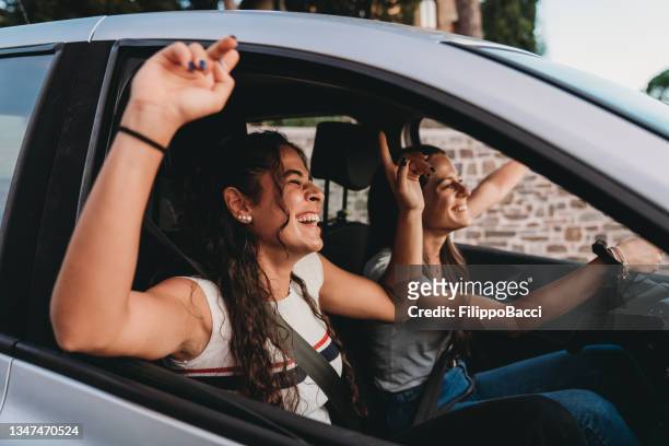 two young adult women are enjoying a car trip together - friends inside car imagens e fotografias de stock