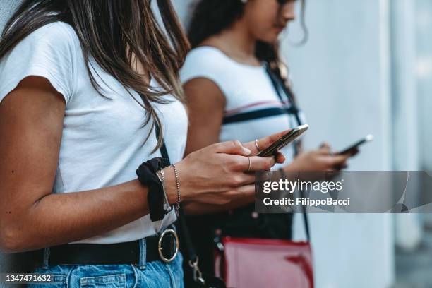 zwei freunde benutzen handys - detail der hände, die die telefone halten - fake news stock-fotos und bilder