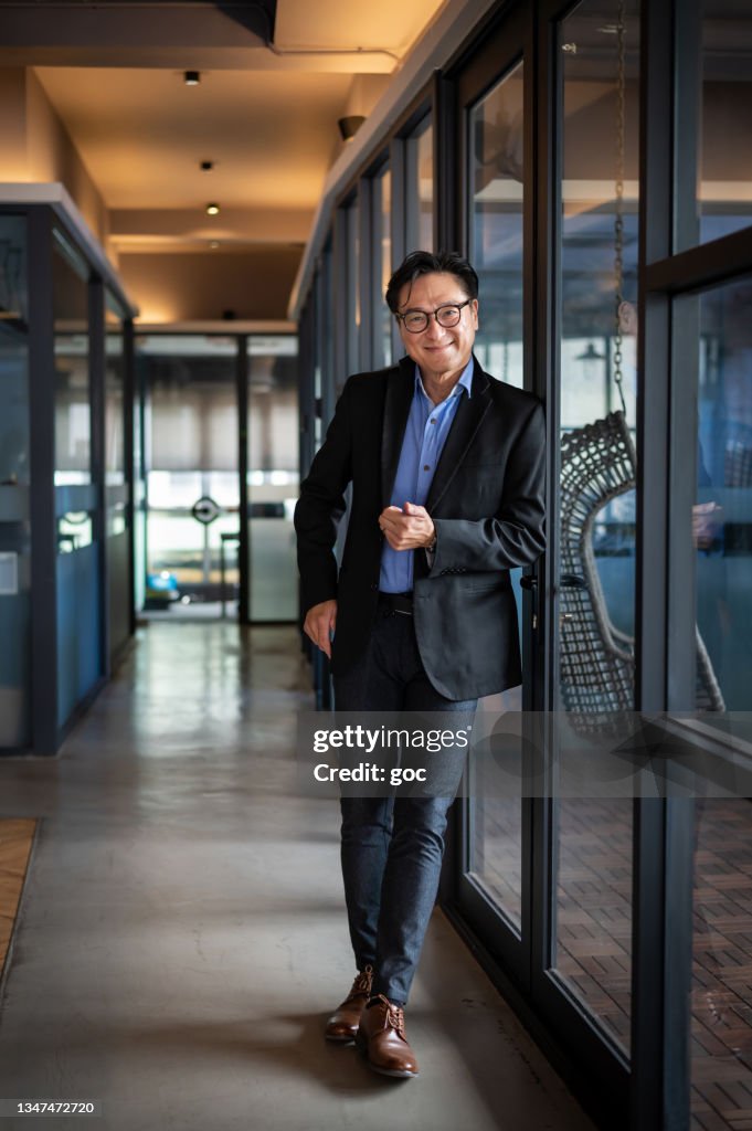 Portrait of handsome Asian businessman looking at camera in modern office