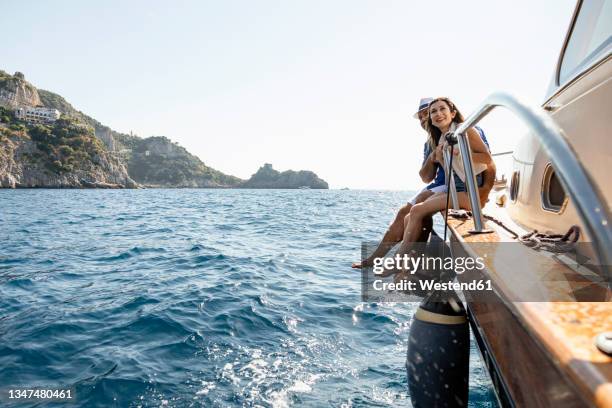 happy couple sitting at motorboat's edge in amalfi coast, italy - power boat stock pictures, royalty-free photos & images