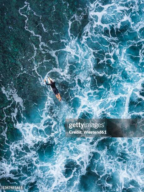 man lying on surfboard while swimming in ocean at huraa island, maldives - open water swimming stock pictures, royalty-free photos & images