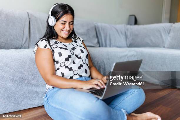 happy woman using laptop in living room - chubby arab stock pictures, royalty-free photos & images