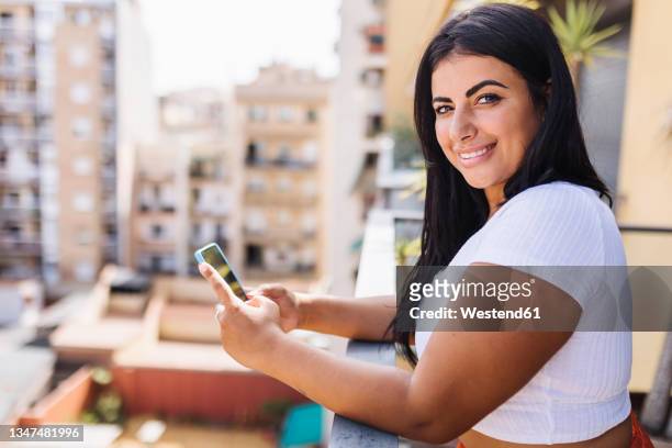 beautiful smiling woman with smart phone in balcony - chubby arab stock pictures, royalty-free photos & images