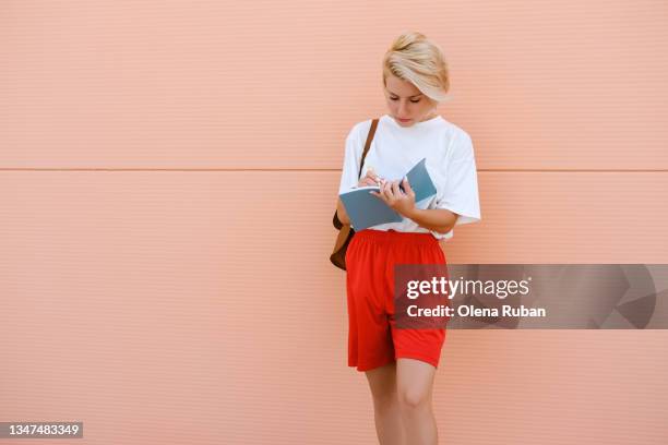 young woman writing in notebook. - rosa handtasche stock-fotos und bilder