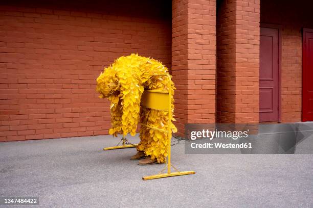 woman in leaf costume leaning on barricade - barricade stock-fotos und bilder