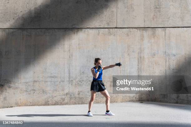 female boxer practicing punching in front of wall - punching wall stock pictures, royalty-free photos & images