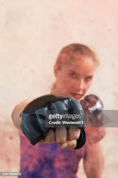 female athlete punching while wearing glove in front of wall - punching stock pictures, royalty-free photos & images