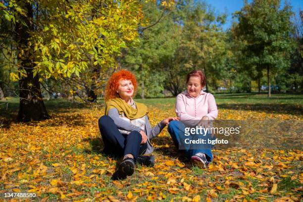 senoir womans talking at the park in autumn - older woman colored hair stock pictures, royalty-free photos & images